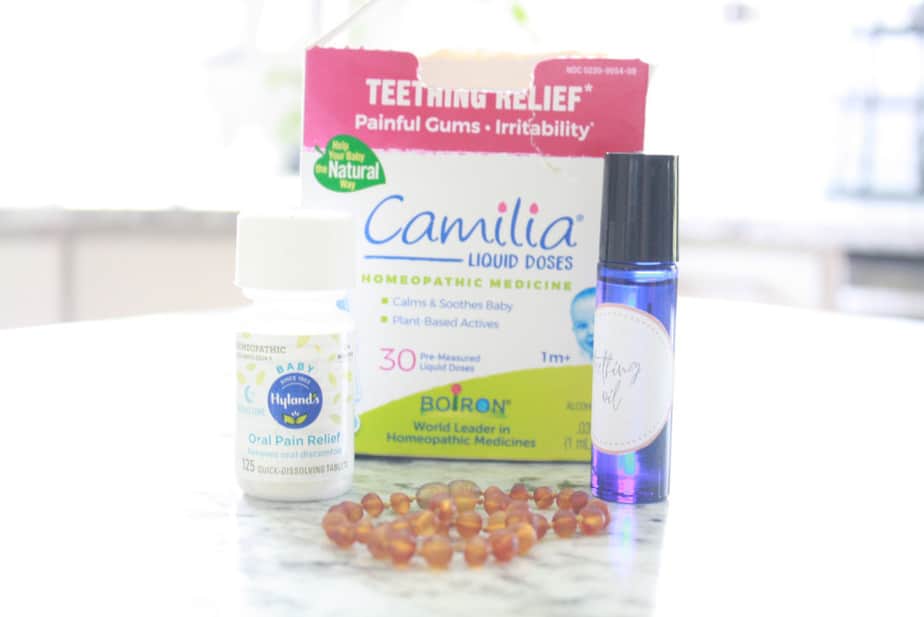 natural teething remedies for babies sitting on kitchen counter. camilia liquid drops, hysland's oral pain relief, and an essential oil roller bottle.