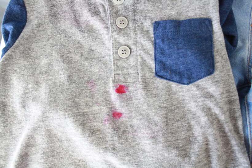 Boy's gray and blue shirt laying on washing machine with hot pink lipstick smeared on.