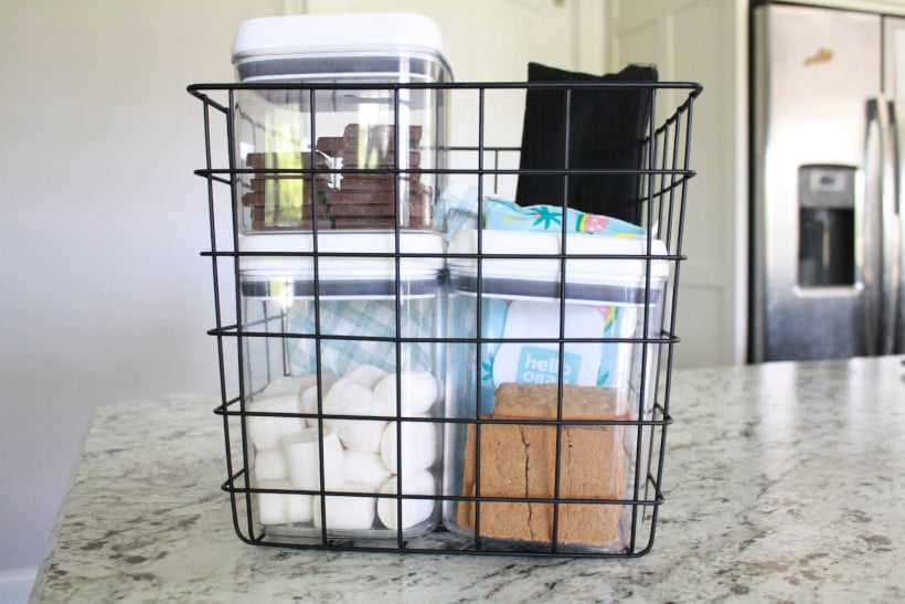 Easy DIY s'mores kit for the family displayed with supplies in metal wire basket on kitchen counter.