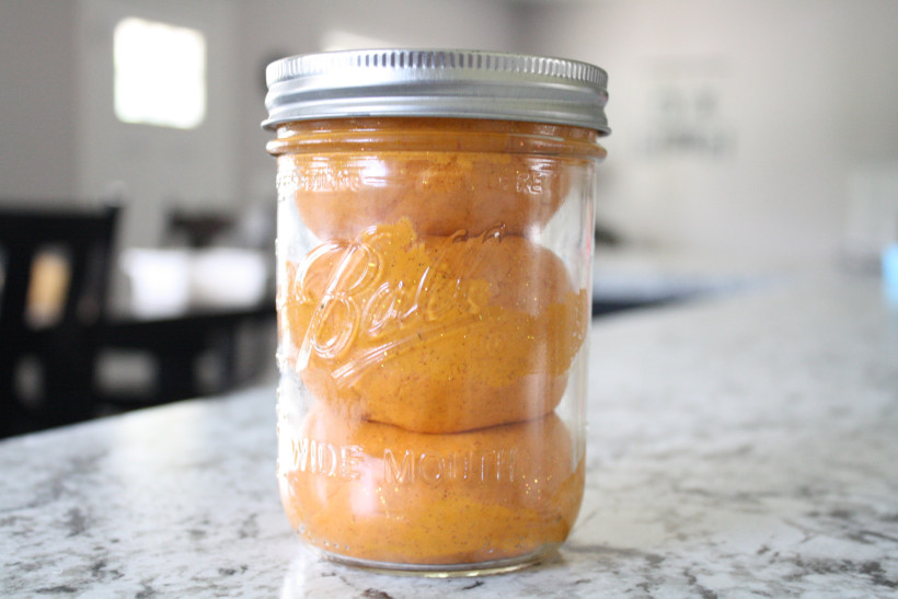 Homemade orange playdough in mason jar on kitchen counter for sensory spring activity for kids.