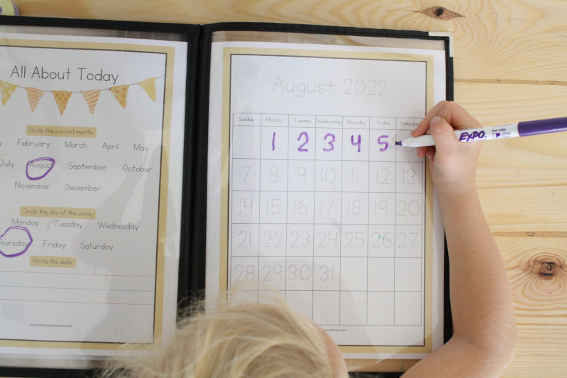 Child filling in the August 2022 calendar.