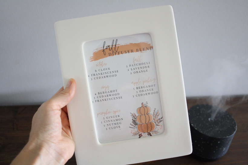 Woman holding picture frame of free printable with the best fall diffuser blends.