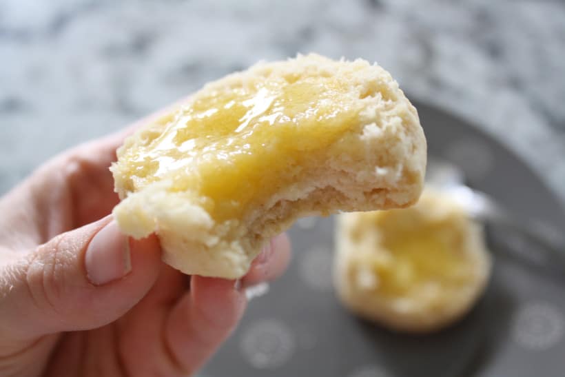 Woman holding fresh biscuit with butter.