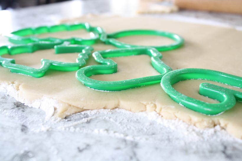 Cookie dough on floured kitchen counter with Christmas cookie cutters on top.