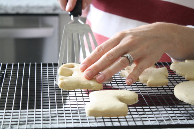 Woman moving sugar cookies to cooling rack.