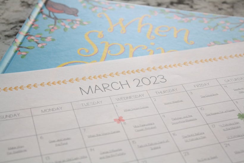 March 2023 reading calendar for free printable displayed on top of Spring book. 