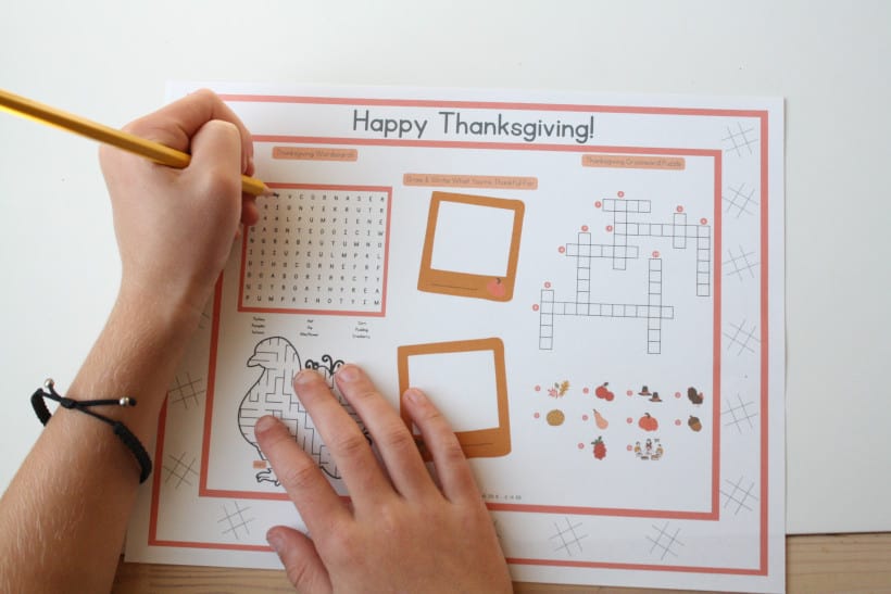 Child is playing the wordsearch on the Thanksgiving activity sheet.