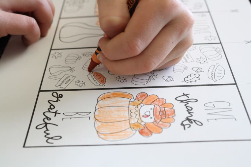 Child coloring in free printable Thanksgiving bookmarks at kitchen table with oranges and browns.