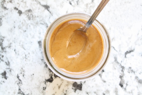 Pumpkin sauce in glass jar with spoon looking from above.
